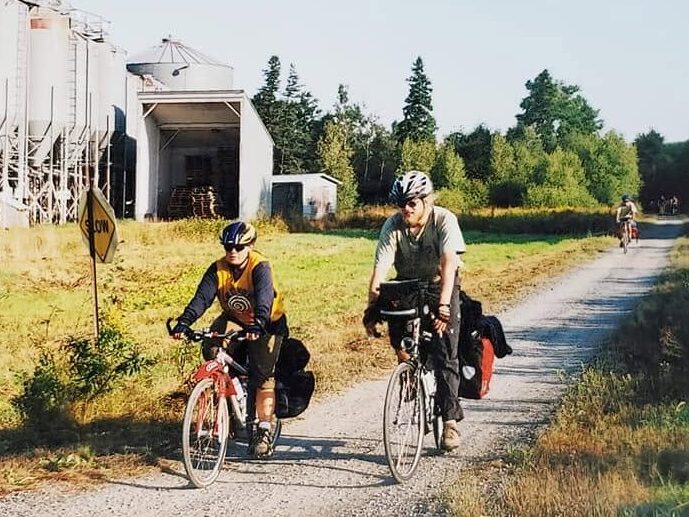 Friends cycling with loaded touring bikes on a rural road during the 2001 Climate Change Caravan.